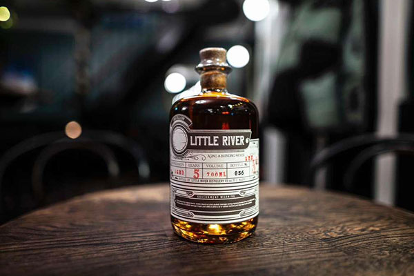 Little River rum bottle standing on a barrel-top table