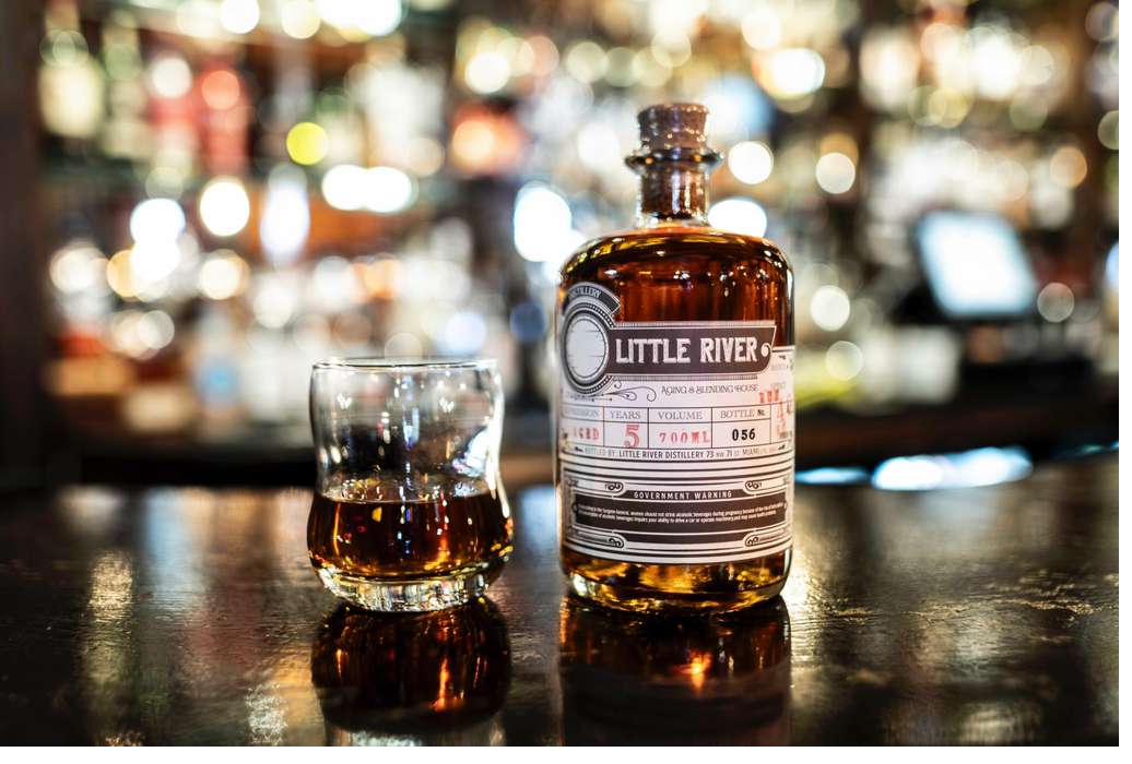 A bottle of Little River rum and a poured glass on the bar