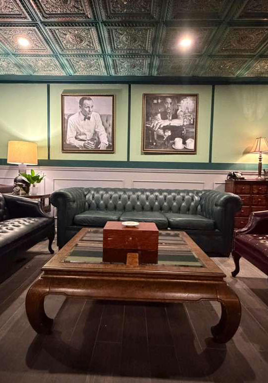 The green lounge — chesterfield sofas beneath framed portraits